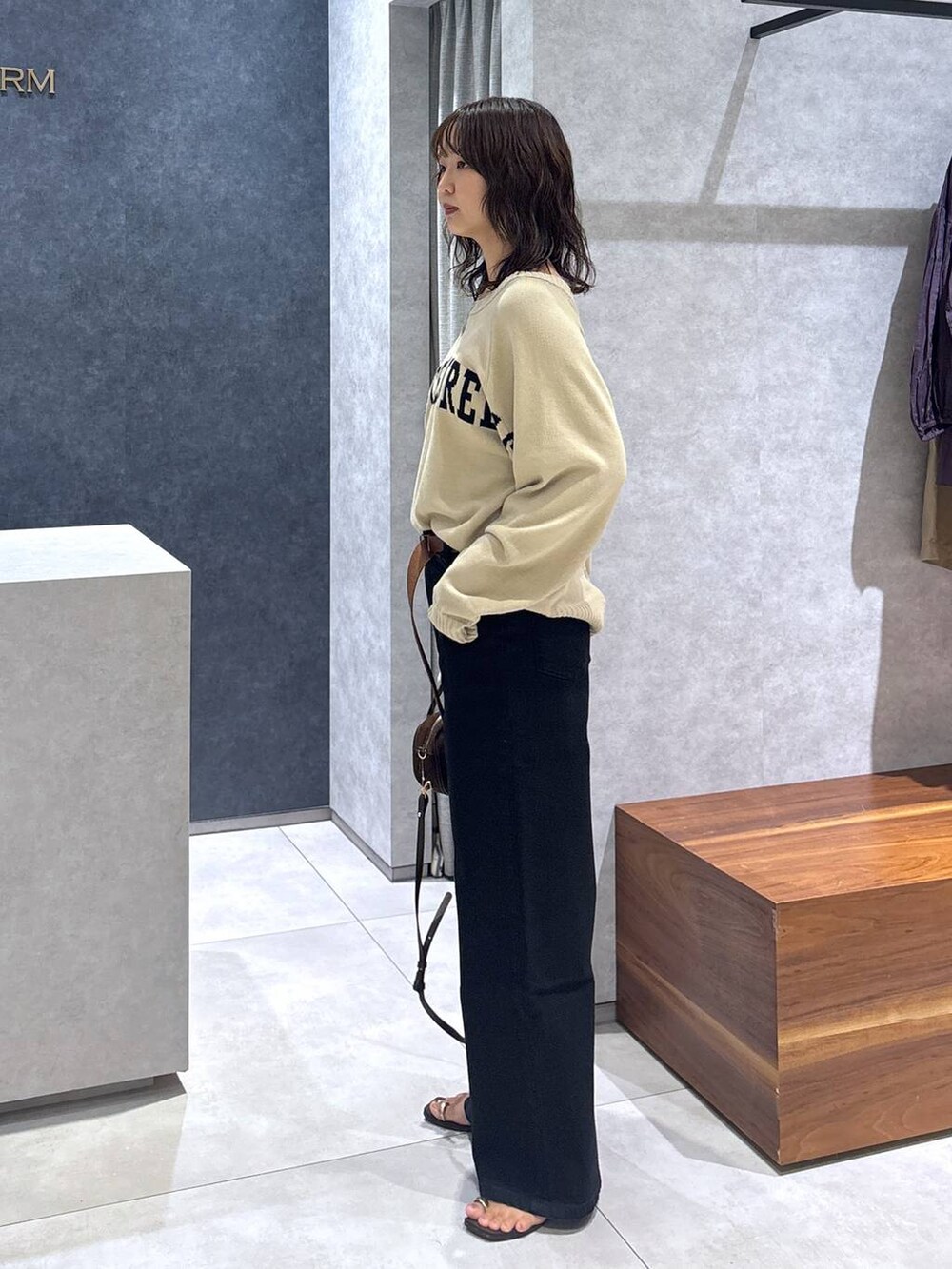 ブラック系のデニムパンツ、ベージュ系のカーディガン/ボレロ、ブラウン系のショルダーバッグを着用したレディースの夏コーディネートの3枚目の写真