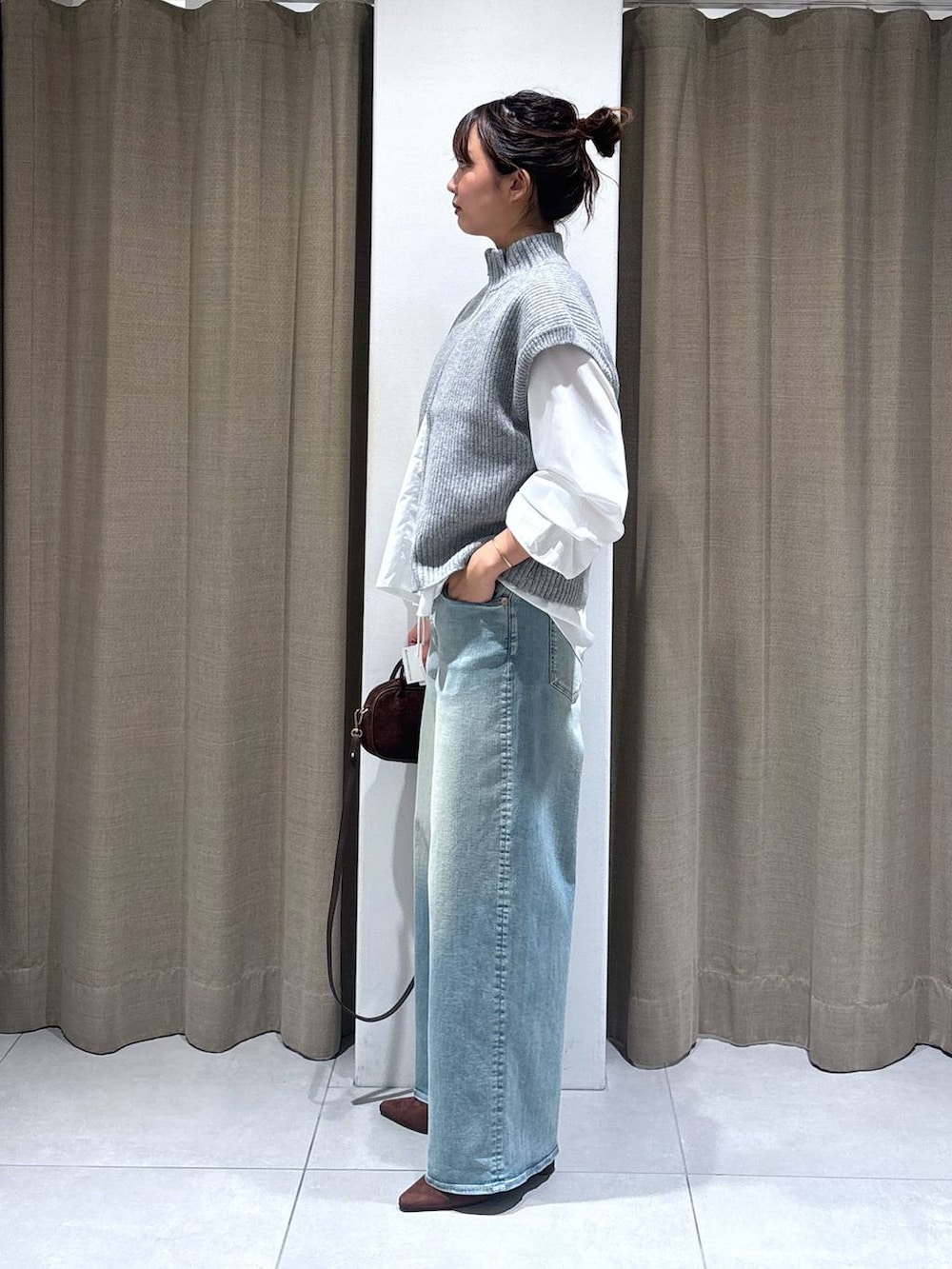 ブルー系のデニムパンツ、ホワイト系のシャツ/ブラウス、ブラウン系のショルダーバッグを着用したレディースの秋コーディネートの2枚目の写真