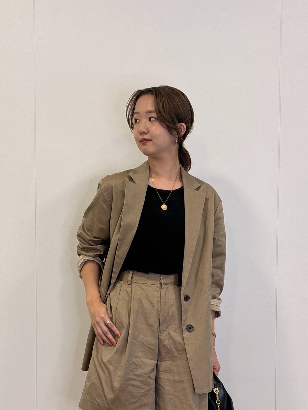 ブラック系のショルダーバッグ、ブラック系のTシャツ/カットソー、ベージュ系のテーラードジャケットを着用したレディースの秋コーディネートの2枚目の写真