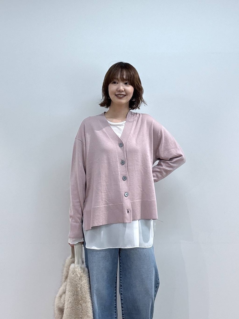 ベージュ系のショルダーバッグ、ブルー系のデニムパンツ、ホワイト系のTシャツ/カットソーを着用したレディースの秋コーディネートの2枚目の写真