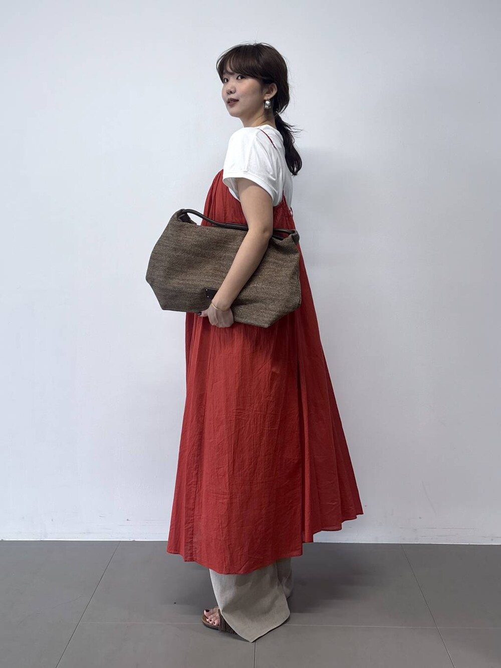 ベージュ系のその他パンツ、オレンジ系のワンピース、ブラウン系のトートバッグを着用したレディースの春コーディネートの2枚目の写真