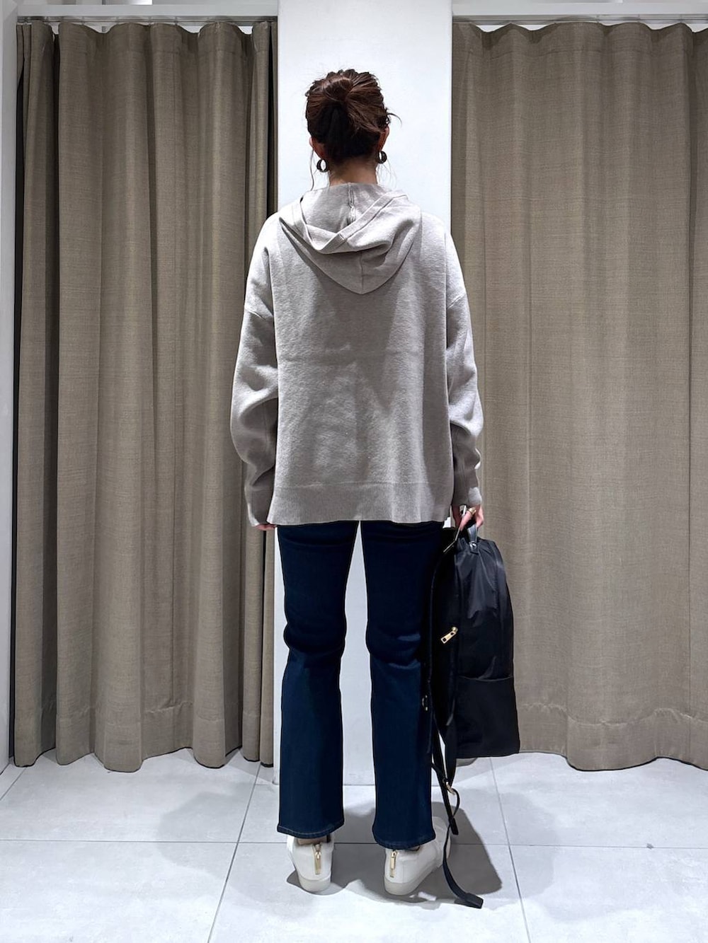 ブラック系のバックパック/リュック、ベージュ系のニット/セーター、ブルー系のデニムパンツを着用したレディースの秋コーディネートの5枚目の写真