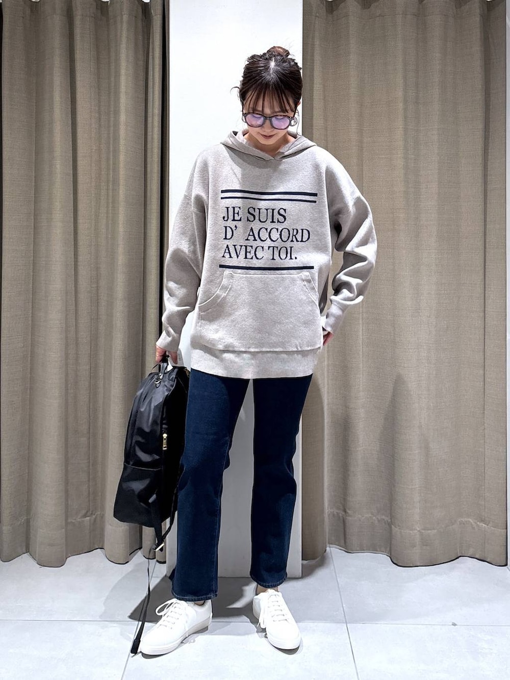 ブラック系のバックパック/リュック、ベージュ系のニット/セーター、ブルー系のデニムパンツを着用したレディースの秋コーディネートの4枚目の写真