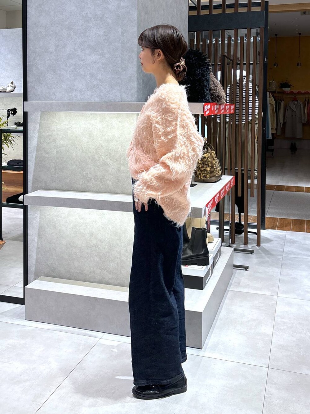 ブルー系のデニムパンツ、ピンク系のカーディガン/ボレロ、ブラック系のショルダーバッグを着用したレディースの冬コーディネートの3枚目の写真