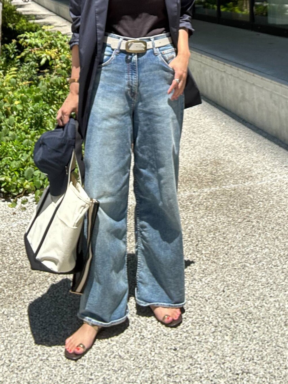 ホワイト系のショルダーバッグ、ブルー系のデニムパンツ、ブルー系のテーラードジャケットを着用したレディースの夏コーディネートの5枚目の写真