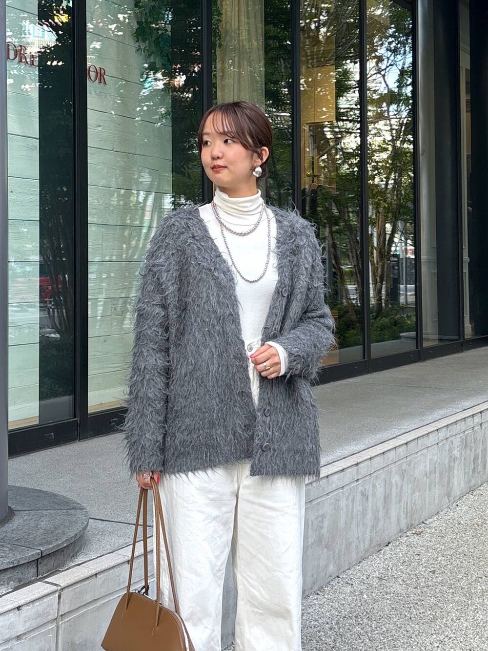 イエロー系のトートバッグ、シルバー系のパンプス、ホワイト系のデニムパンツを着用したレディースの秋コーディネートの2枚目の写真