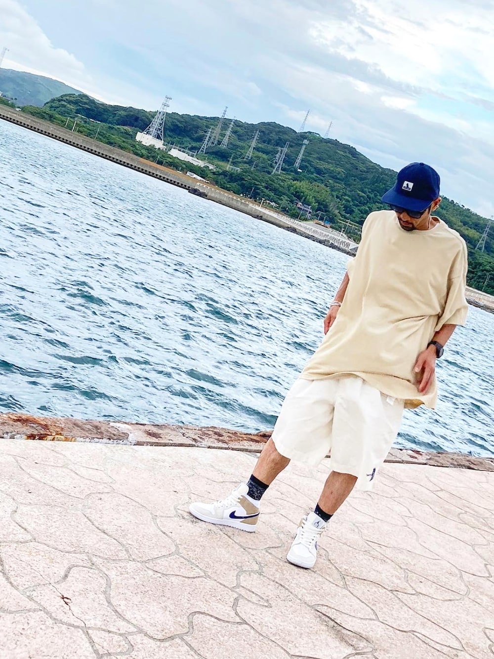 ベージュ系のTシャツ/カットソー、ホワイト系のチノパンツ、ベージュ系のスニーカーを着用したメンズの夏コーディネートの3枚目の写真