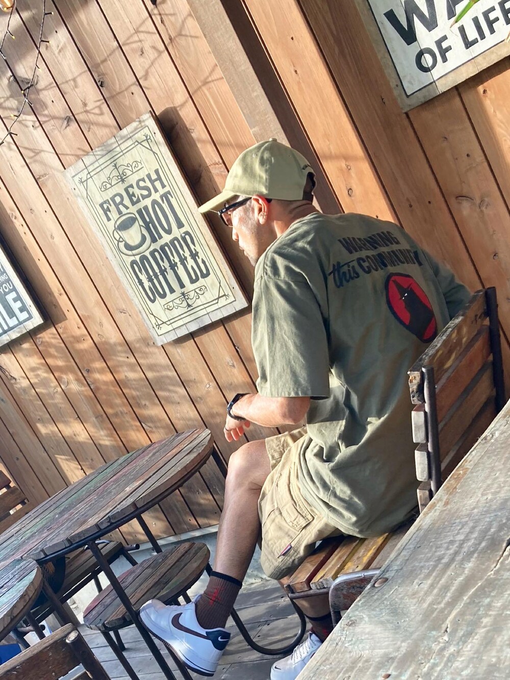 グリーン系のTシャツ/カットソー、ベージュ系のチノパンツ、ホワイト系のスニーカーを着用したメンズの夏コーディネートの2枚目の写真