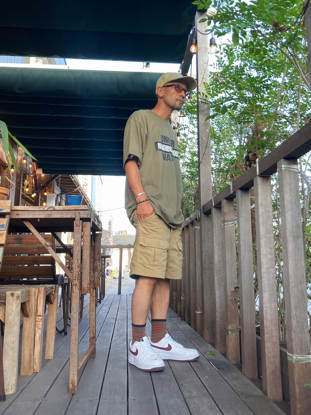 グリーン系のTシャツ/カットソー、ベージュ系のチノパンツ、ホワイト系のスニーカーを着用したメンズの夏コーディネートの3枚目の写真