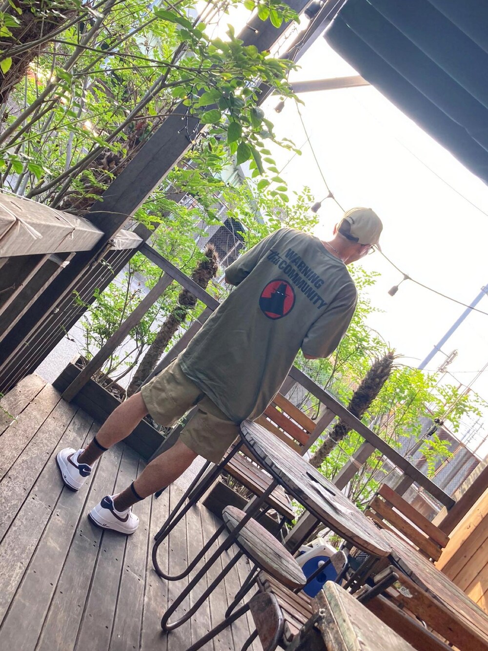 グリーン系のTシャツ/カットソー、ベージュ系のチノパンツ、ホワイト系のスニーカーを着用したメンズの夏コーディネートの4枚目の写真