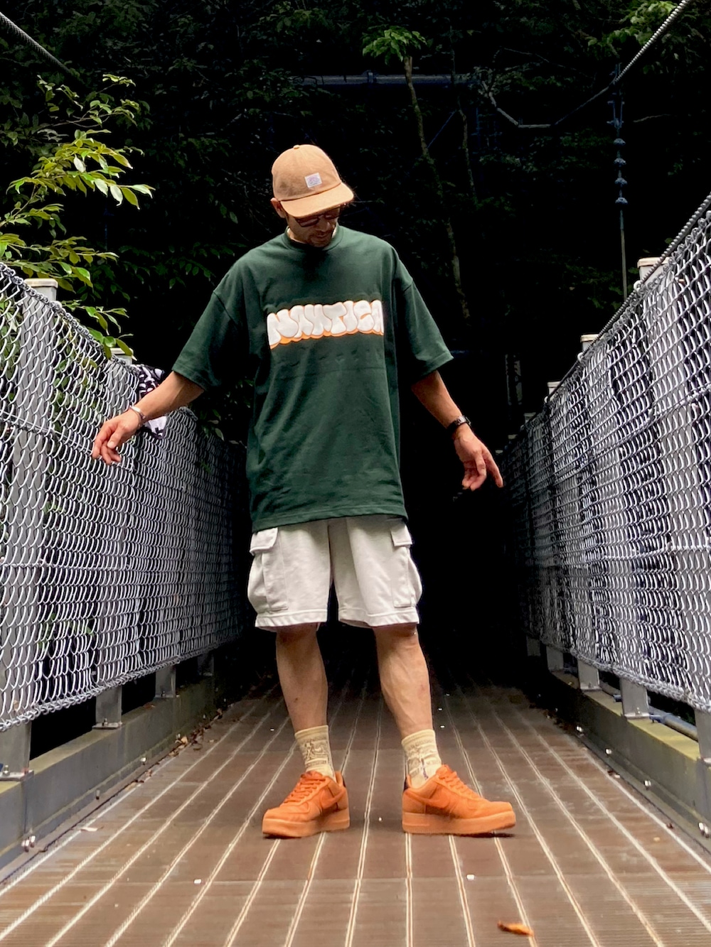 グリーン系のTシャツ/カットソー、グレー系のカーゴパンツ、ブラウン系のスニーカーを着用したメンズの夏コーディネートの2枚目の写真