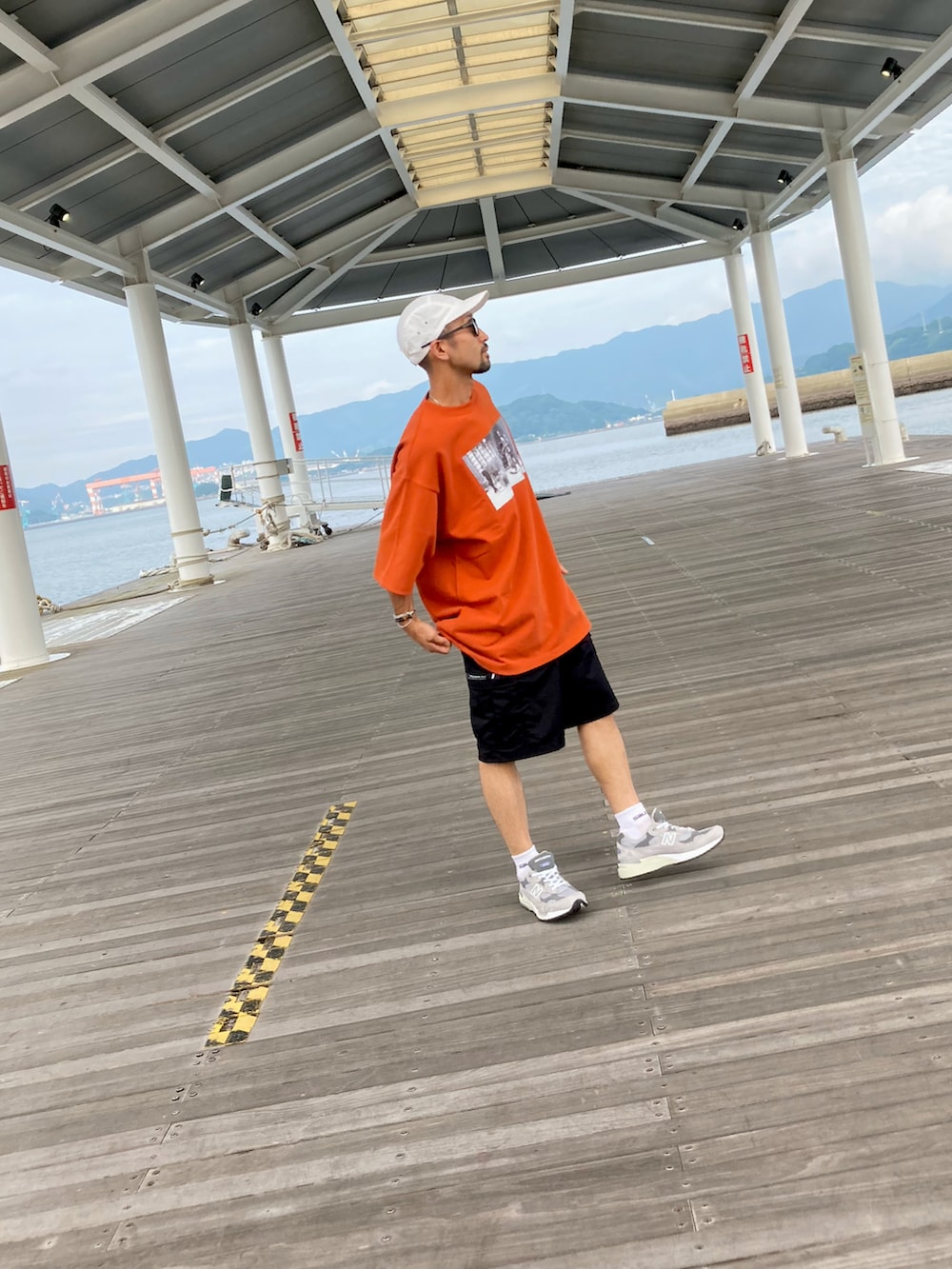 ブラウン系のTシャツ/カットソー、ブラック系のカーゴパンツ、グレー系のスニーカーを着用したメンズの夏コーディネートの2枚目の写真