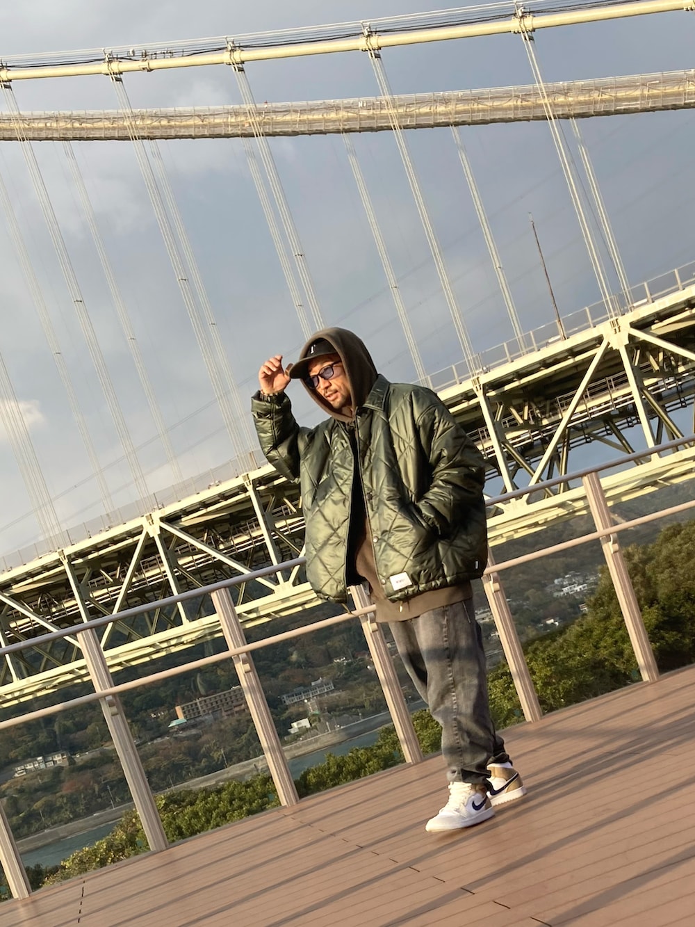 グリーン系のパーカー、グリーン系のミリタリージャケット、グレー系のデニムパンツを着用したメンズの冬コーディネートの2枚目の写真