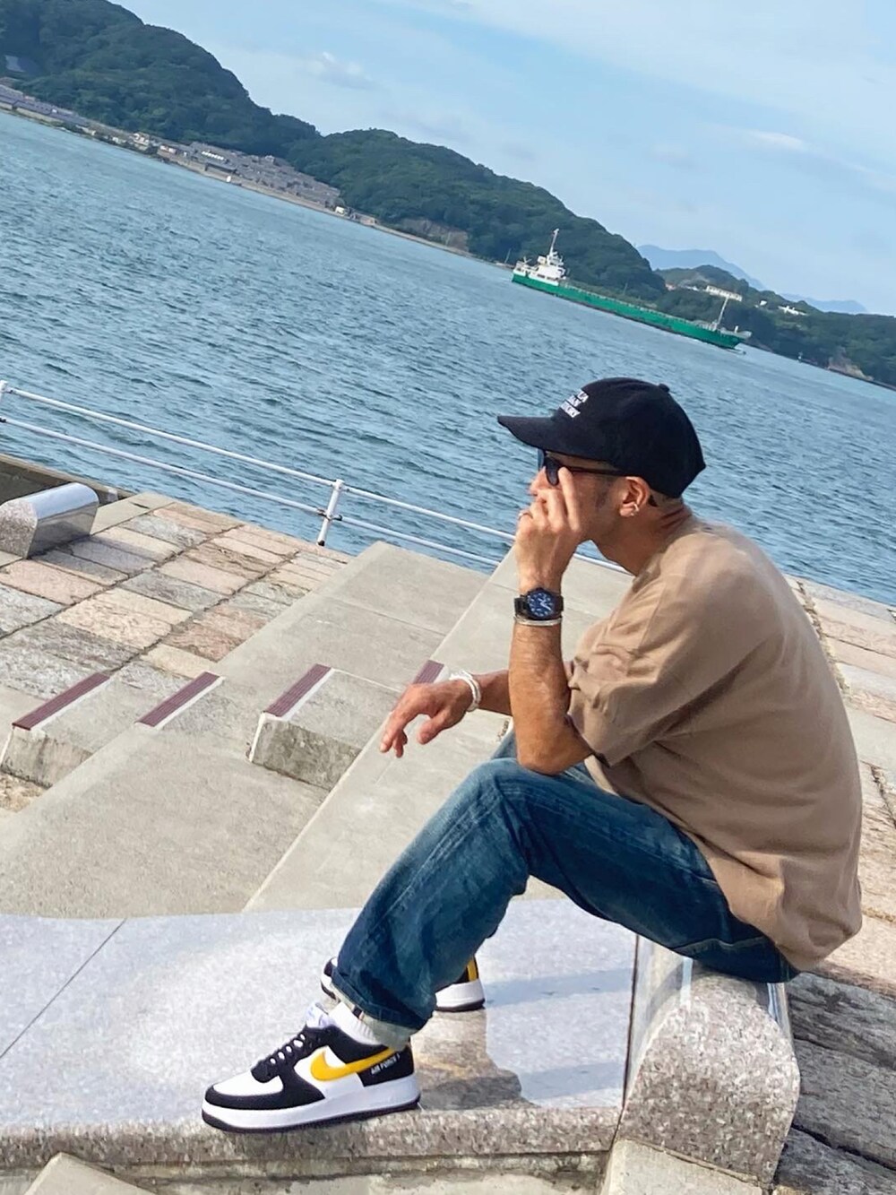 ベージュ系のニット/セーター、ブルー系のデニムパンツ、ブラック系のスニーカーを着用したメンズの秋コーディネートの2枚目の写真