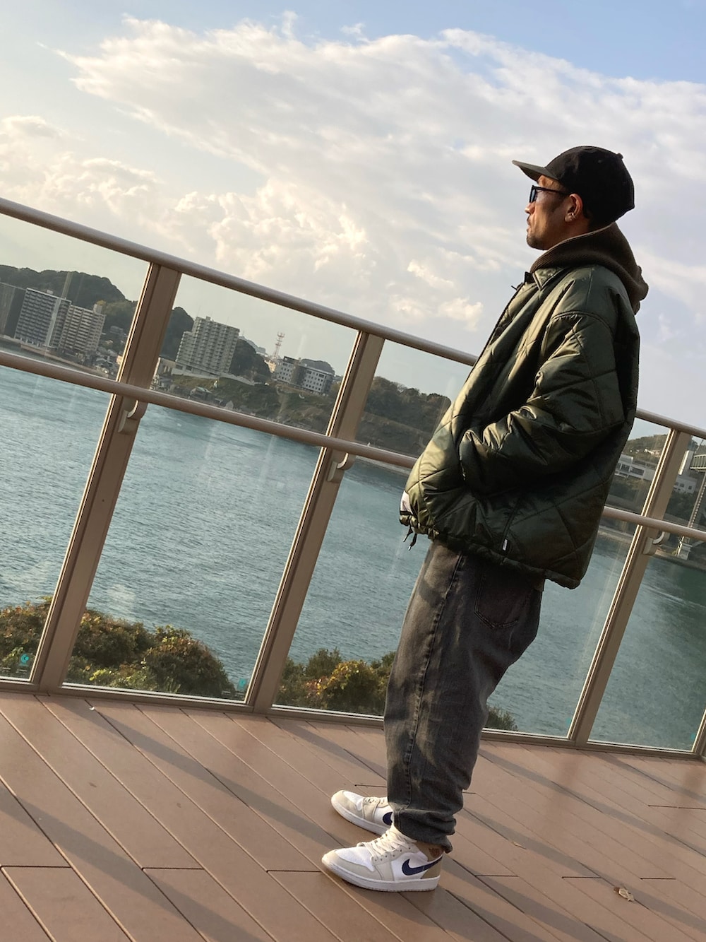 グリーン系のパーカー、グリーン系のミリタリージャケット、グレー系のデニムパンツを着用したメンズの冬コーディネートの3枚目の写真