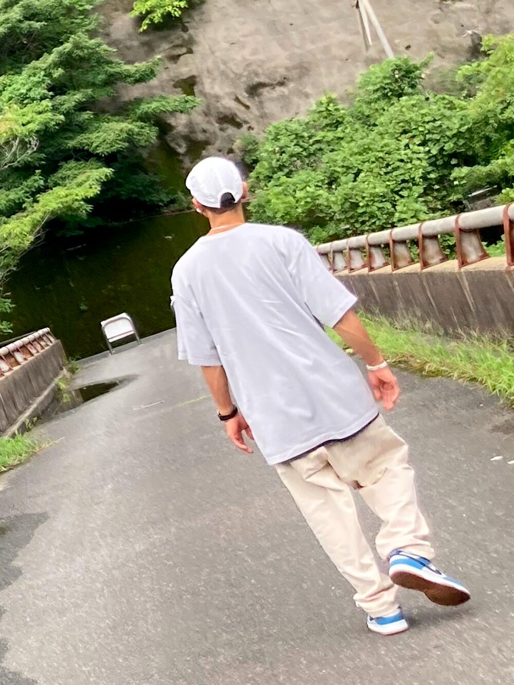 グレー系のTシャツ/カットソー、ベージュ系のチノパンツ、ブルー系のスニーカーを着用したメンズの夏コーディネートの3枚目の写真