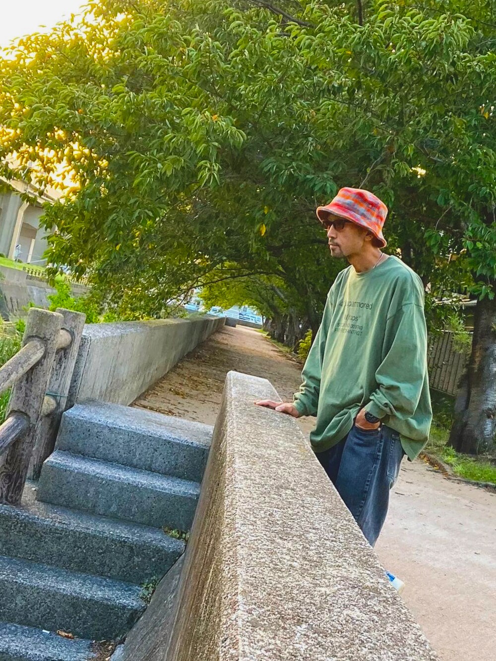 グリーン系のTシャツ/カットソー、グレー系のデニムパンツ、ブルー系のスニーカーを着用したメンズの秋コーディネートの2枚目の写真