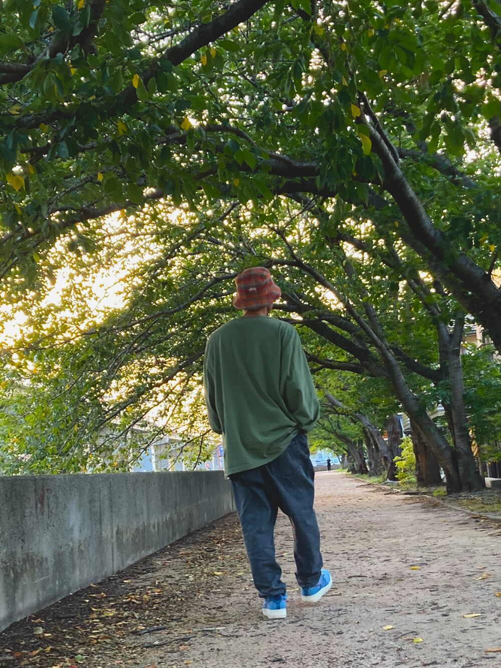 グリーン系のTシャツ/カットソー、グレー系のデニムパンツ、ブルー系のスニーカーを着用したメンズの秋コーディネートの3枚目の写真