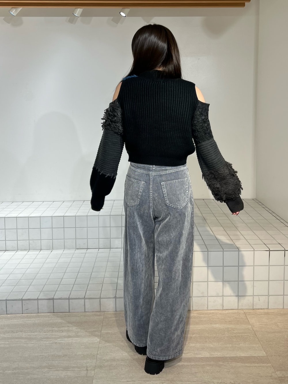 ブラック系のブーツ、グレー系のデニムパンツ、ブラック系のニット/セーターを着用したレディースの秋コーディネートの3枚目の写真