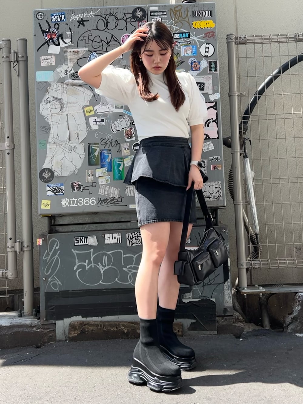ブラック系のブーツ、ブラック系のデニムスカート、ホワイト系のTシャツ/カットソーを着用したレディースの春コーディネートの2枚目の写真