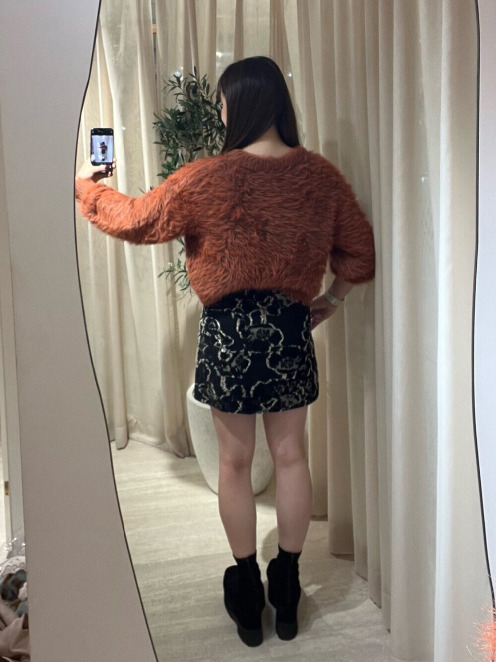 ブラック系のブーツ、ブラック系のスカート、グレー系のニット/セーターを着用したレディースの秋コーディネートの3枚目の写真