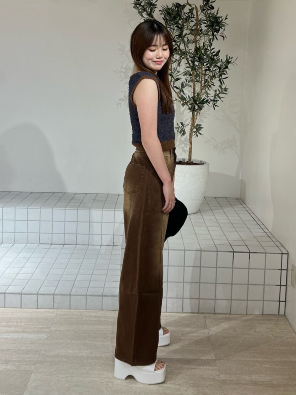 ホワイト系のサンダル、ブラウン系のデニムパンツ、ブラウン系のニット/セーターを着用したレディースの夏コーディネートの2枚目の写真