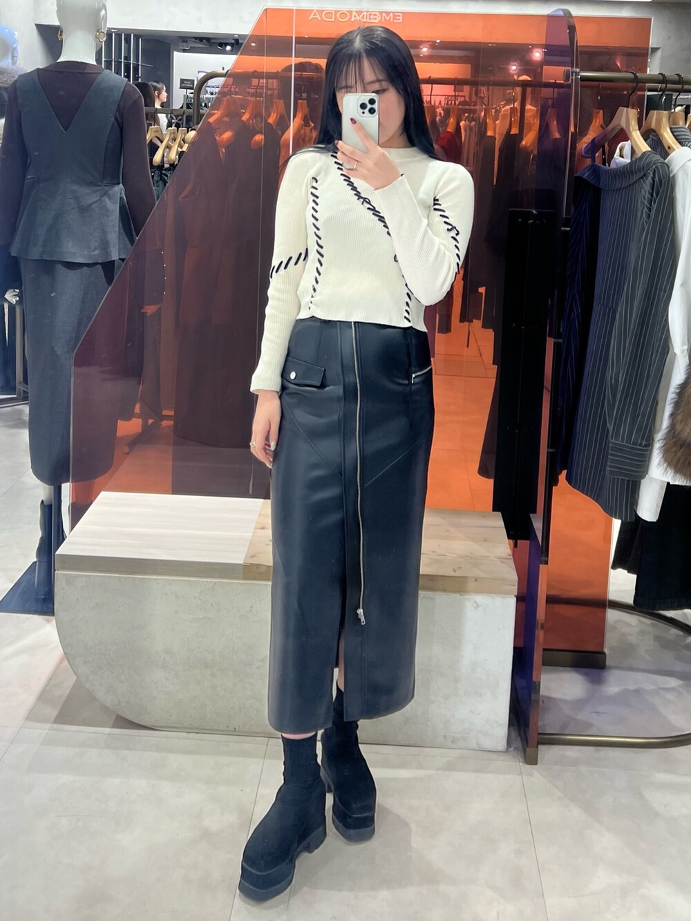 ブラック系のスカート、ホワイト系のニット/セーター、ブラック系のブーツを着用したレディースの秋コーディネートの6枚目の写真