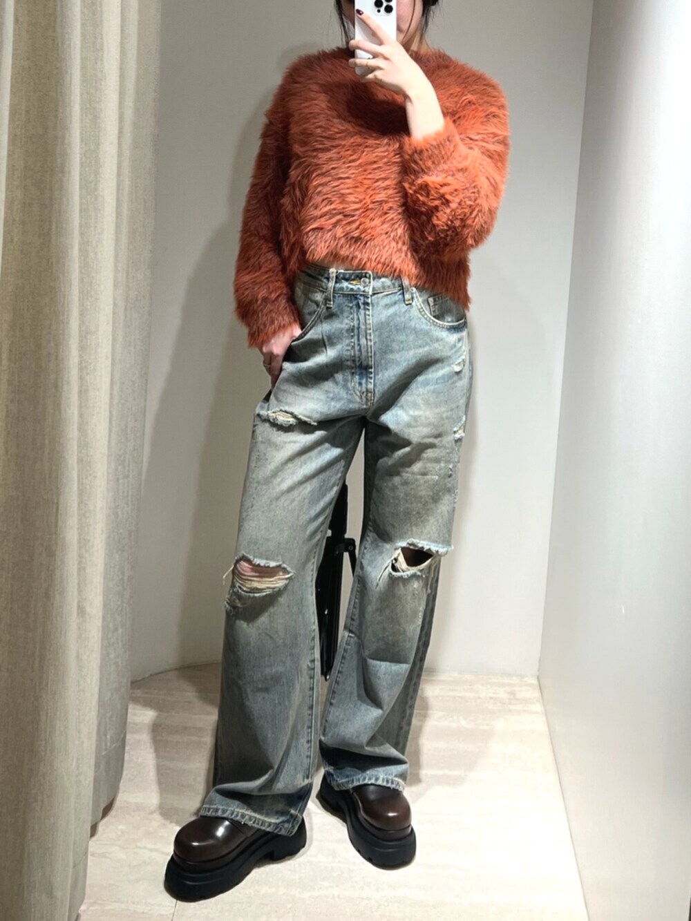 ブルー系のデニムパンツ、オレンジ系のニット/セーター、ブラウン系のサンダルを着用したレディースの秋コーディネートの4枚目の写真