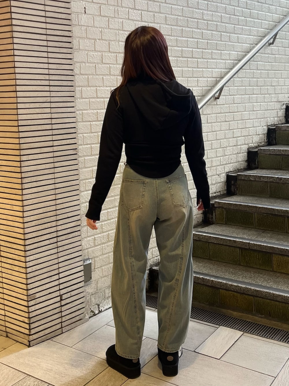 ブルー系のデニムパンツ、ブラック系のブーツ、ブラック系のパーカーを着用したレディースの冬コーディネートの3枚目の写真