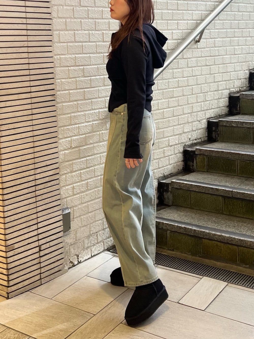 ブルー系のデニムパンツ、ブラック系のブーツ、ブラック系のパーカーを着用したレディースの冬コーディネートの2枚目の写真