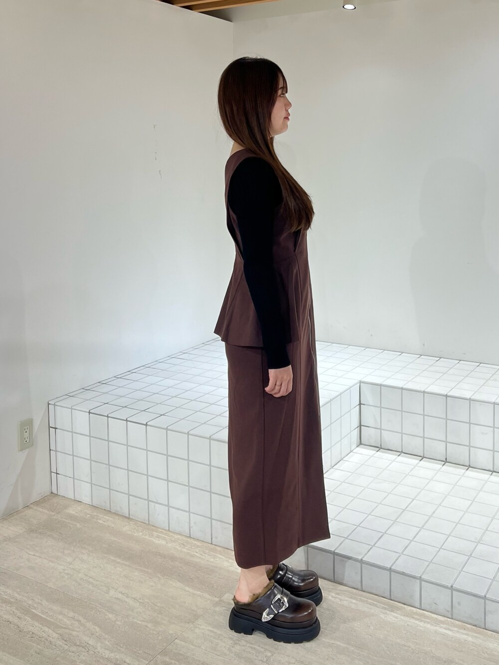 ブラック系のサンダル、ブラック系のジャンパースカート、ブラック系のニット/セーターを着用したレディースの秋コーディネートの2枚目の写真