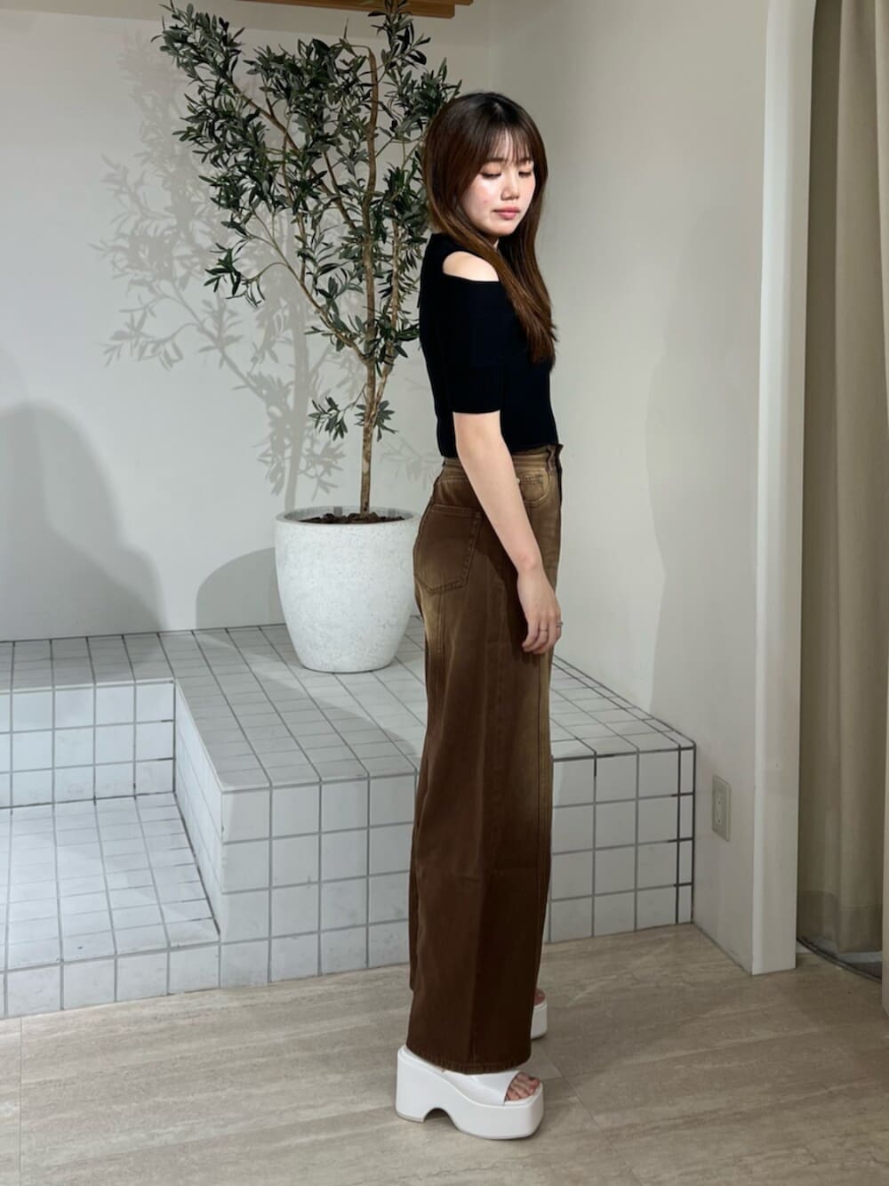 ホワイト系のサンダル、ブラウン系のデニムパンツ、ブラック系のニット/セーターを着用したレディースの夏コーディネートの2枚目の写真