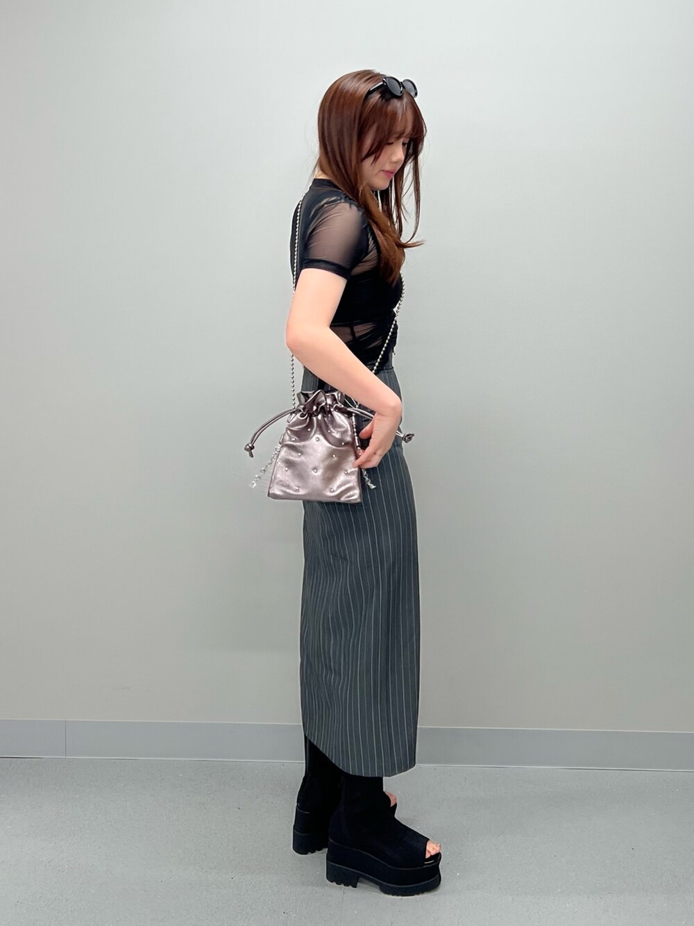 グレー系のスカート、ブラック系のチューブトップ、ブラック系のTシャツ/カットソーを着用したレディースの春コーディネートの2枚目の写真