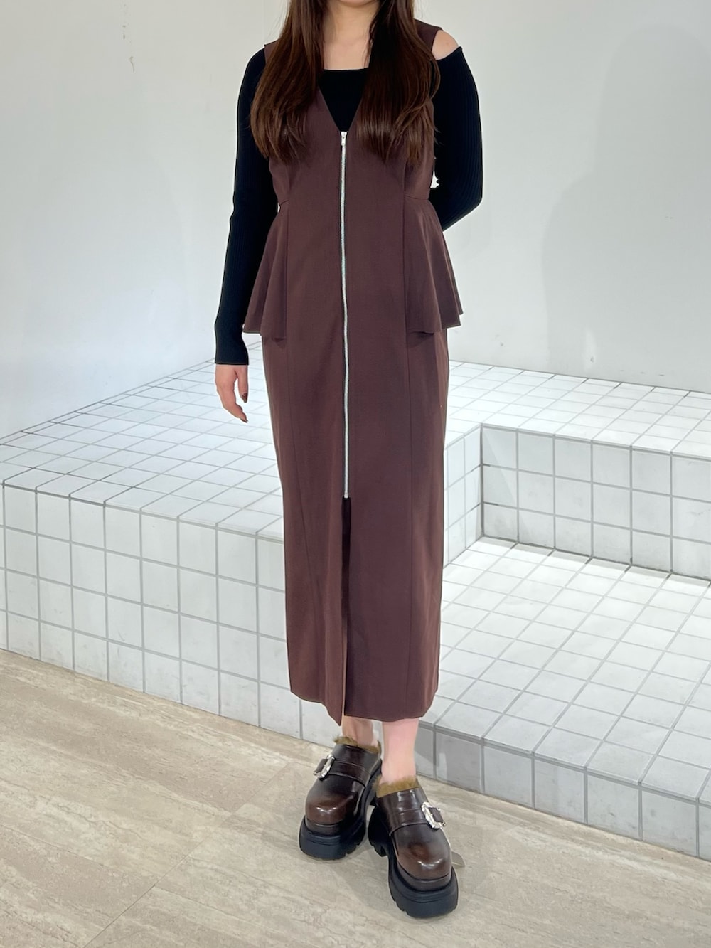 ブラック系のサンダル、ブラック系のジャンパースカート、ブラック系のニット/セーターを着用したレディースの秋コーディネートの6枚目の写真