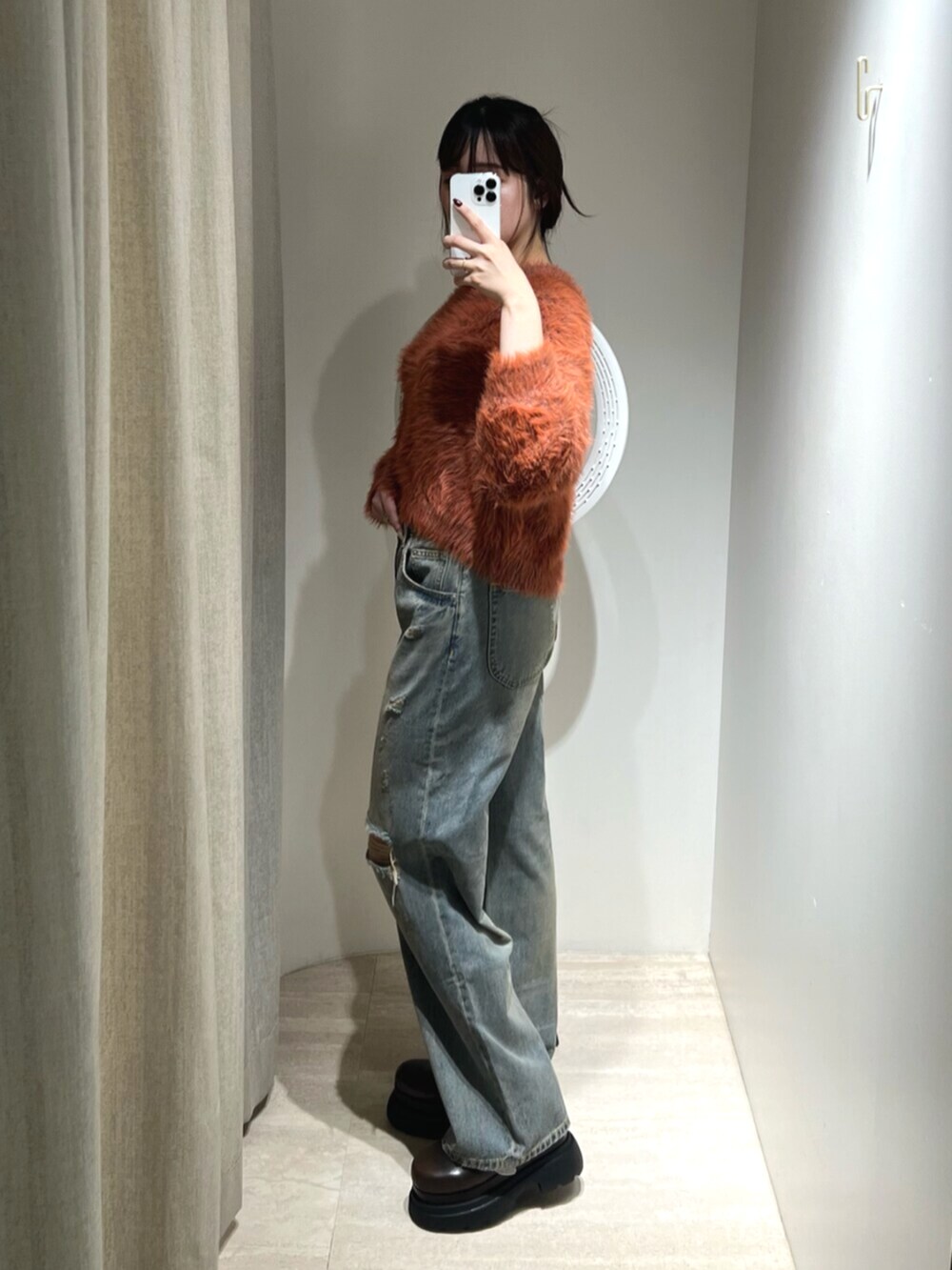 ブルー系のデニムパンツ、オレンジ系のニット/セーター、ブラウン系のサンダルを着用したレディースの秋コーディネートの2枚目の写真