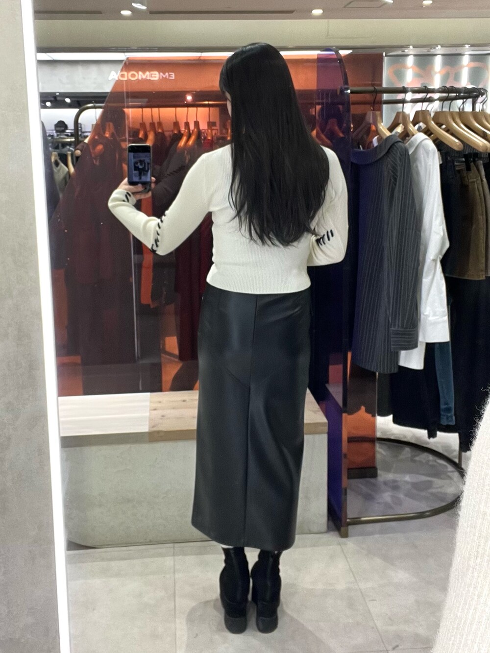 ブラック系のスカート、ホワイト系のニット/セーター、ブラック系のブーツを着用したレディースの秋コーディネートの5枚目の写真