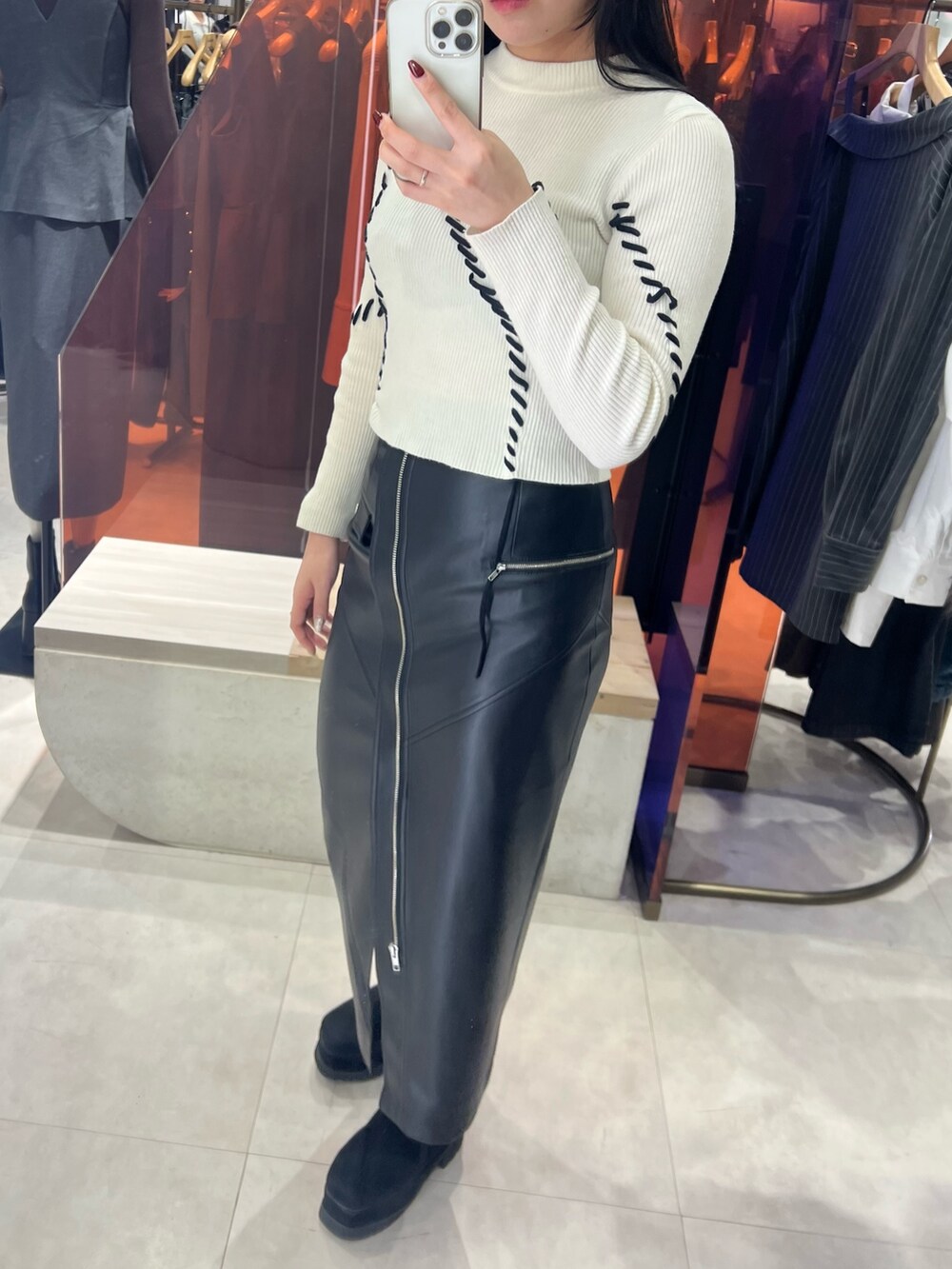 ブラック系のスカート、ホワイト系のニット/セーター、ブラック系のブーツを着用したレディースの秋コーディネートの4枚目の写真