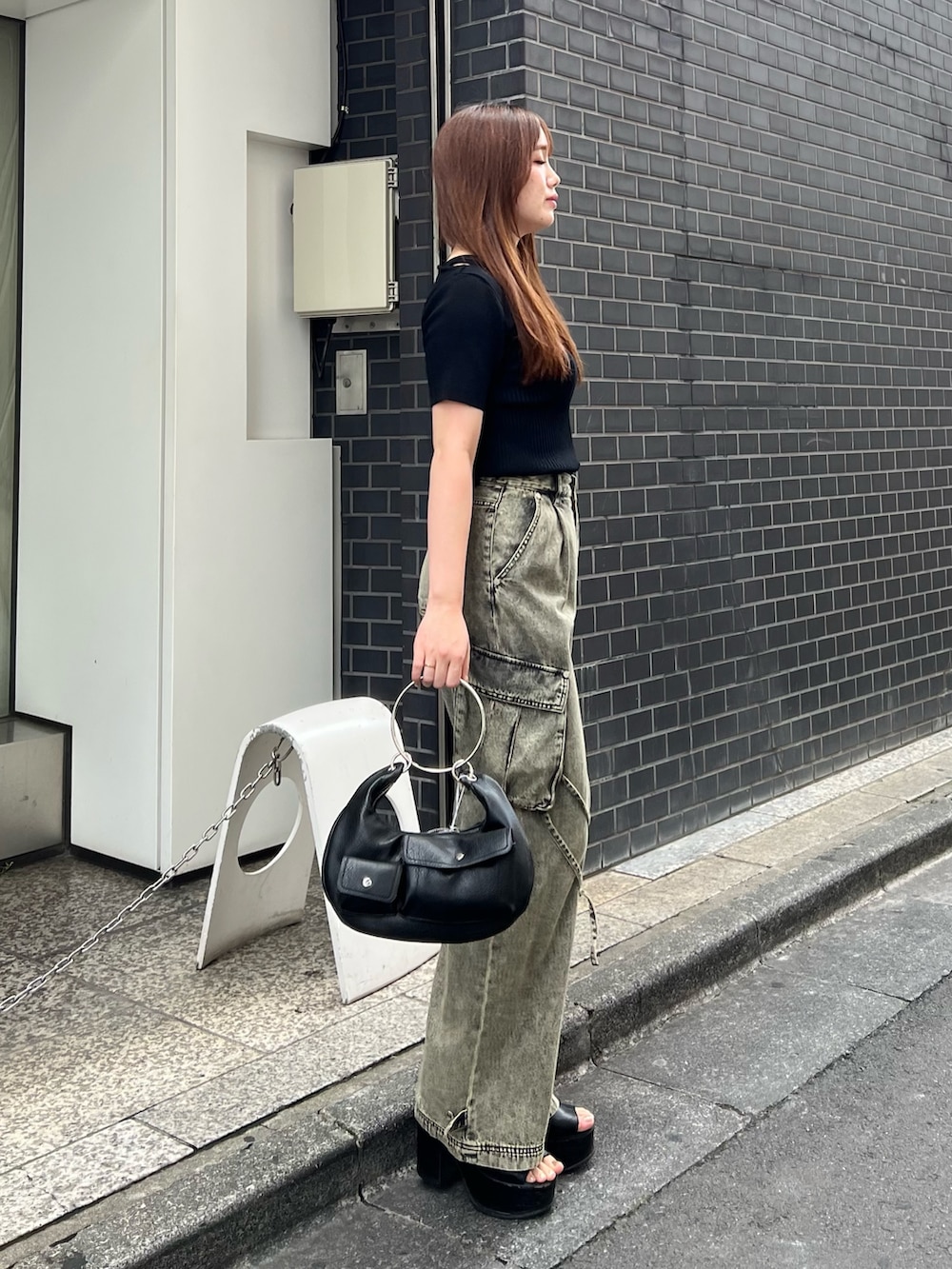 ブラック系のサンダル、ブラック系のハンドバッグ、ブラック系のニット/セーターを着用したレディースの夏コーディネートの2枚目の写真