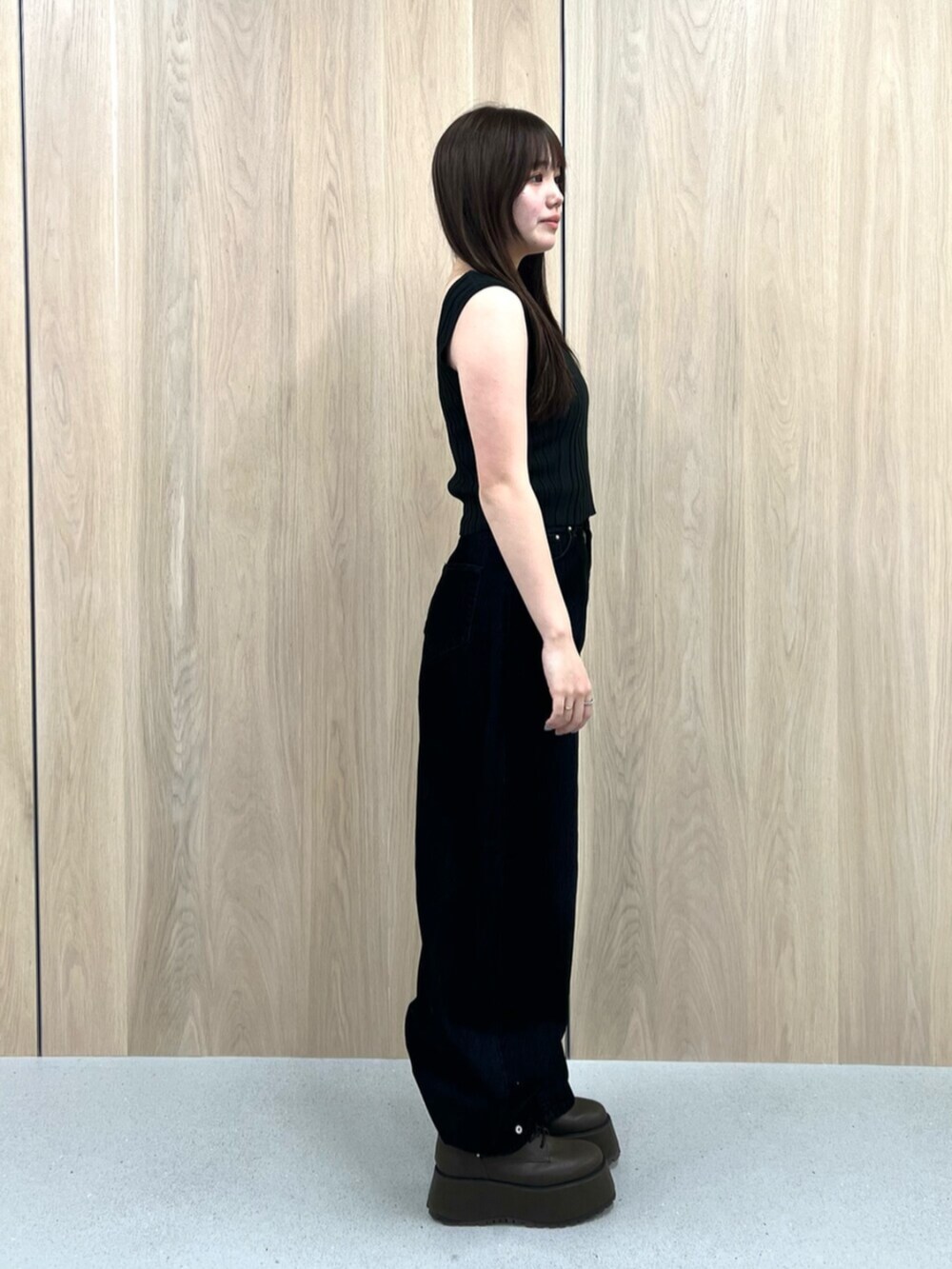 ホワイト系のタンクトップ、ブラウン系のブーツ、ブラック系のデニムパンツを着用したレディースの夏コーディネートの2枚目の写真