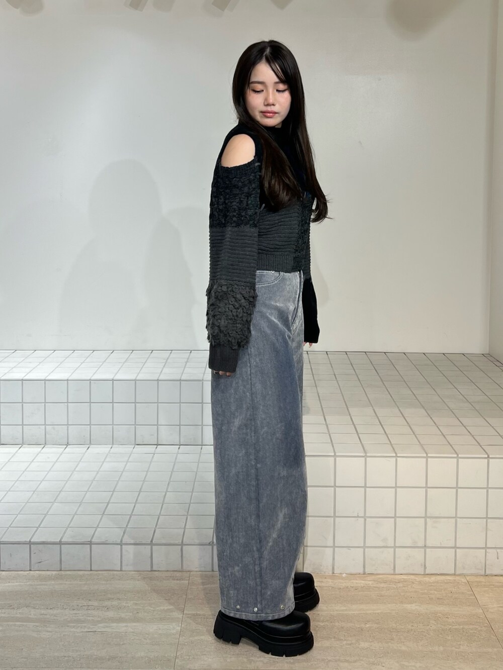 ブラック系のブーツ、グレー系のデニムパンツ、ブラック系のニット/セーターを着用したレディースの秋コーディネートの2枚目の写真