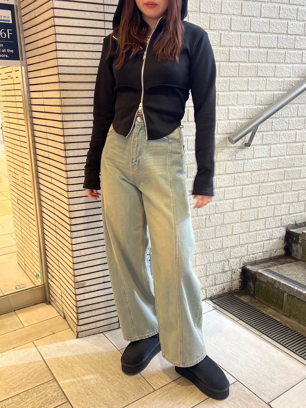 ブルー系のデニムパンツ、ブラック系のブーツ、ブラック系のパーカーを着用したレディースの冬コーディネートの4枚目の写真