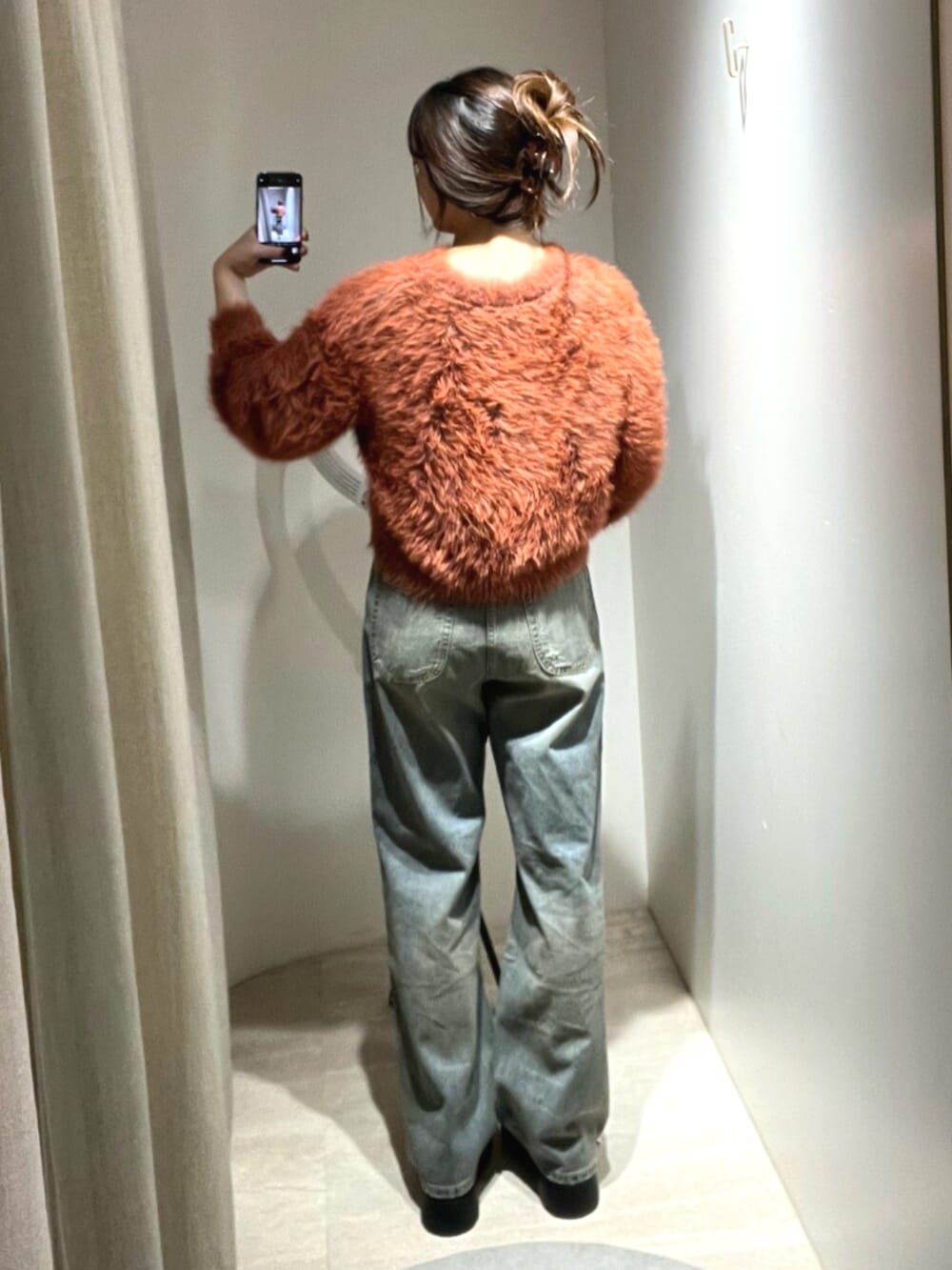 ブルー系のデニムパンツ、オレンジ系のニット/セーター、ブラウン系のサンダルを着用したレディースの秋コーディネートの3枚目の写真