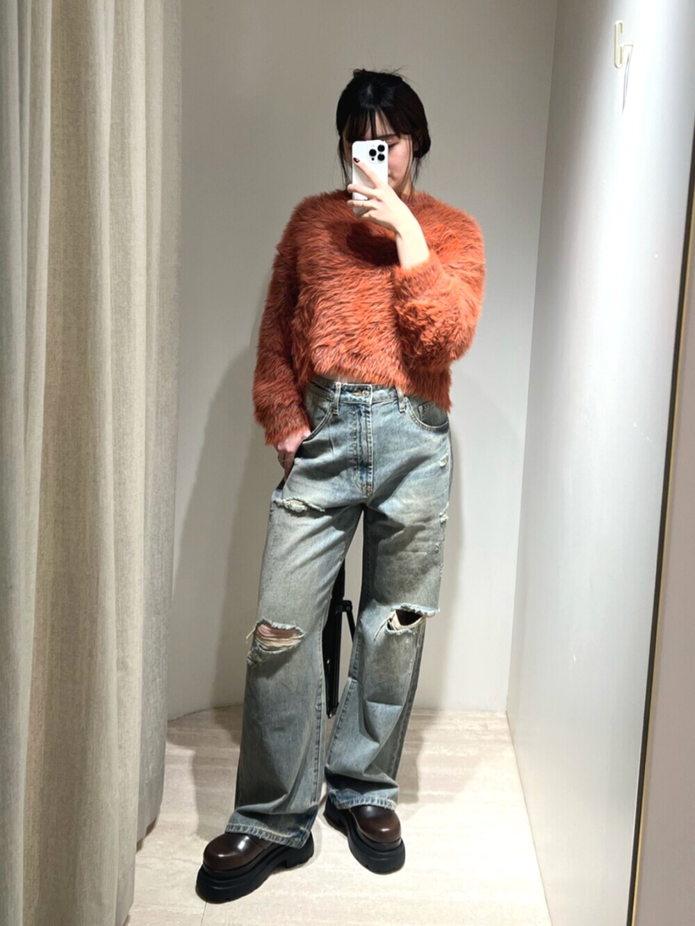ブルー系のデニムパンツ、オレンジ系のニット/セーター、ブラウン系のサンダルを着用したレディースの秋コーディネートの6枚目の写真