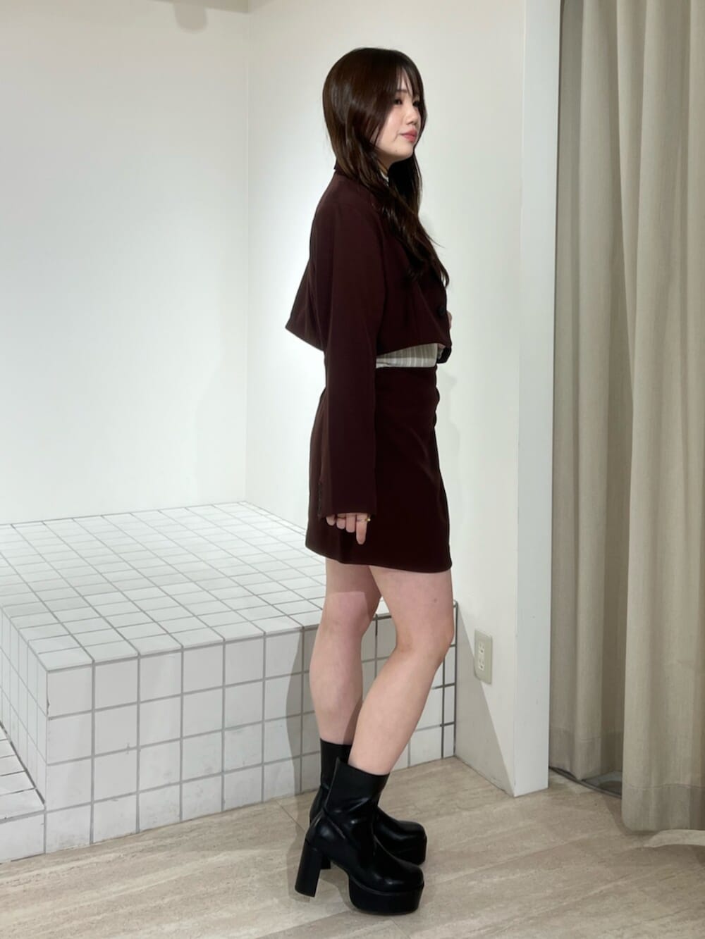 レッド系のスカート、レッド系のテーラードジャケット、ブラック系のブーツを着用したレディースの秋コーディネートの2枚目の写真