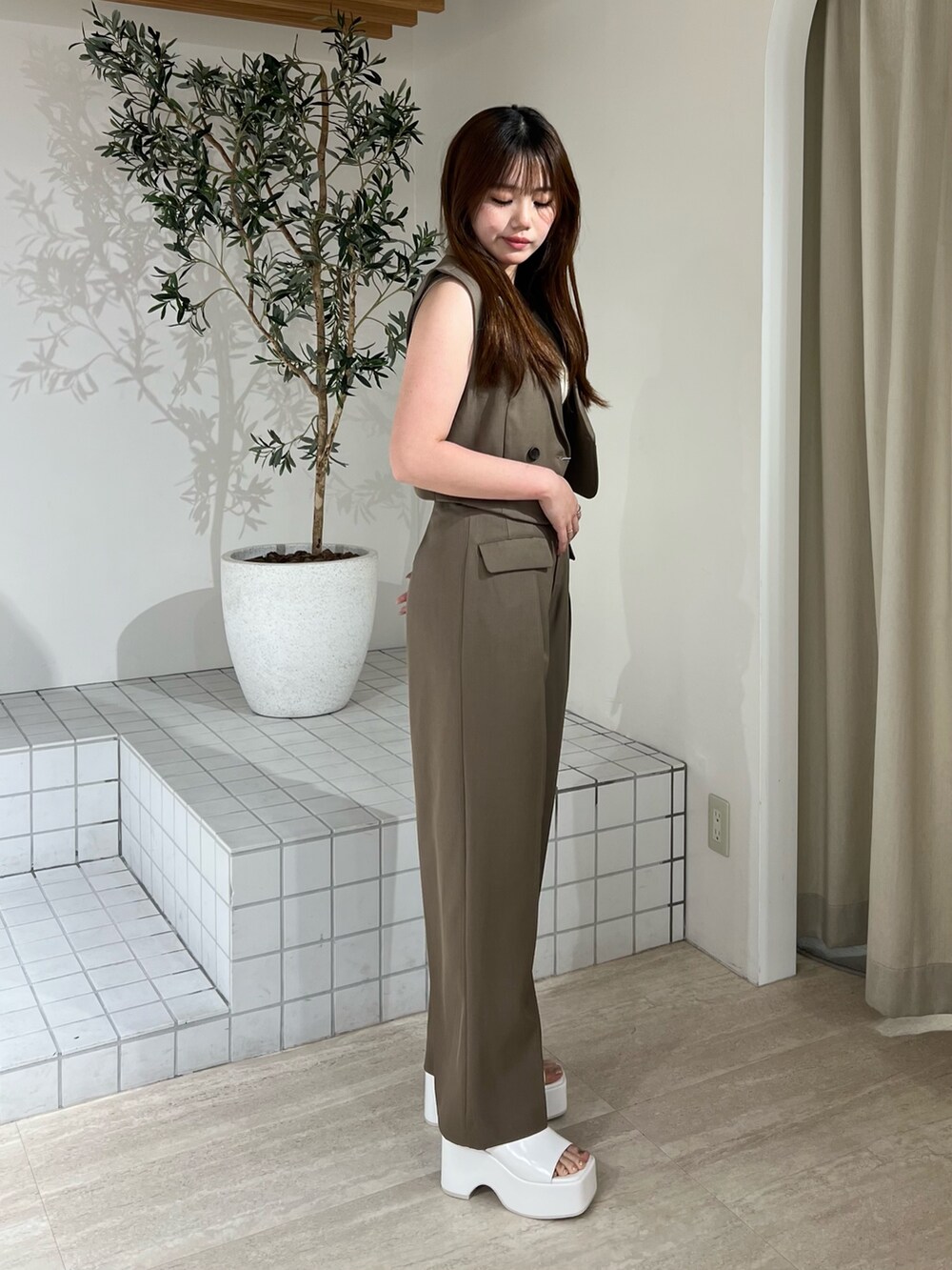 ホワイト系のサンダル、ブラウン系のベスト、ブラウン系のその他パンツを着用したレディースの夏コーディネートの2枚目の写真