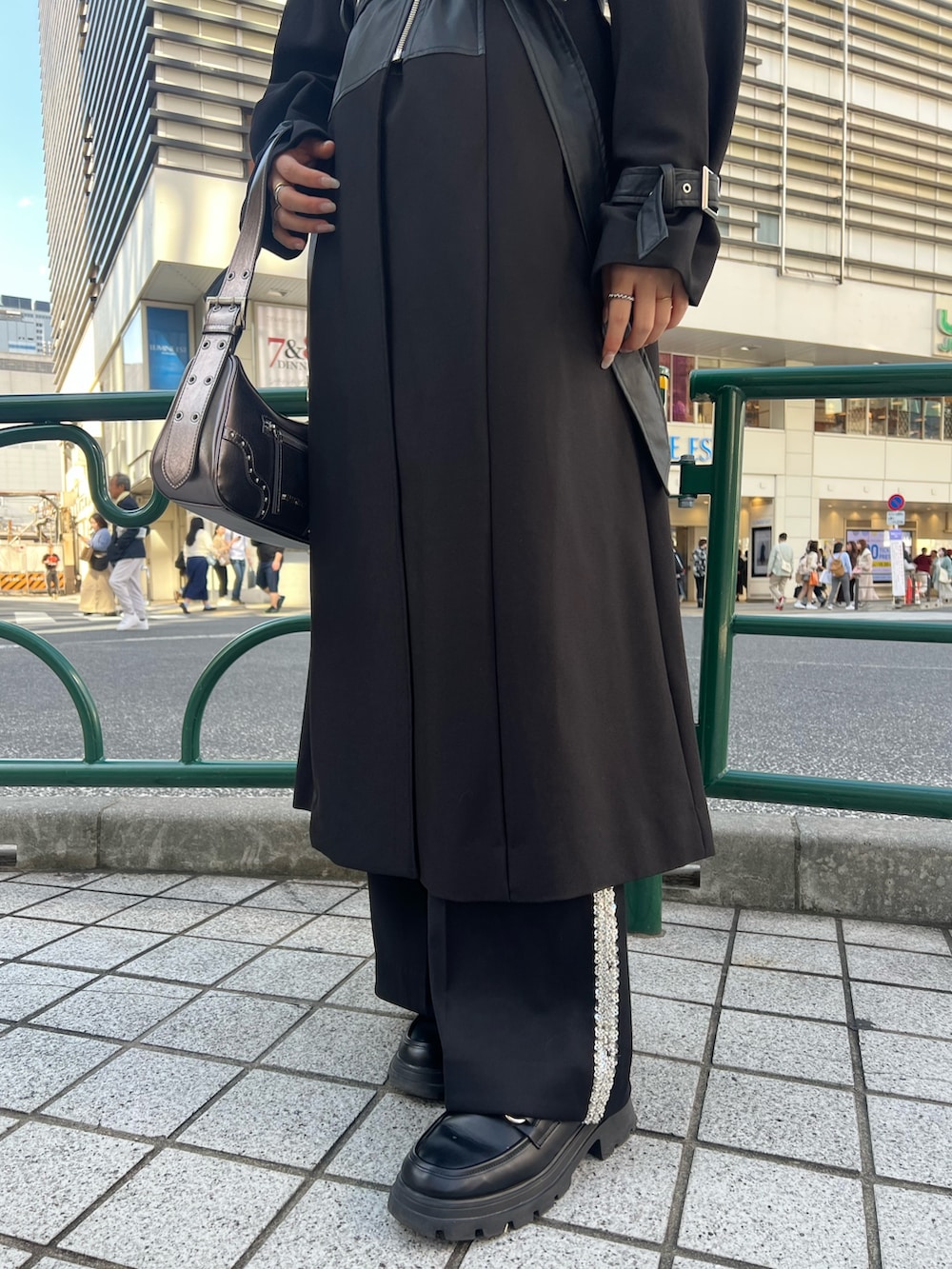 ブラック系のその他パンツ、ブラック系のトレンチコート、ゴールド系のハンドバッグを着用したレディースの秋コーディネートの6枚目の写真