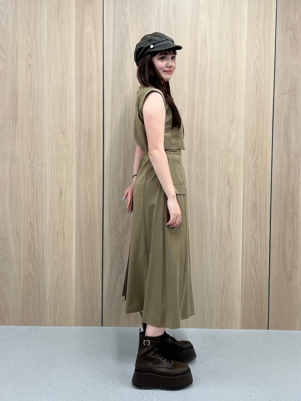 ブラウン系のブーツ、グリーン系のワンピース、ベージュ系のキャスケットを着用したレディースの夏コーディネートの2枚目の写真