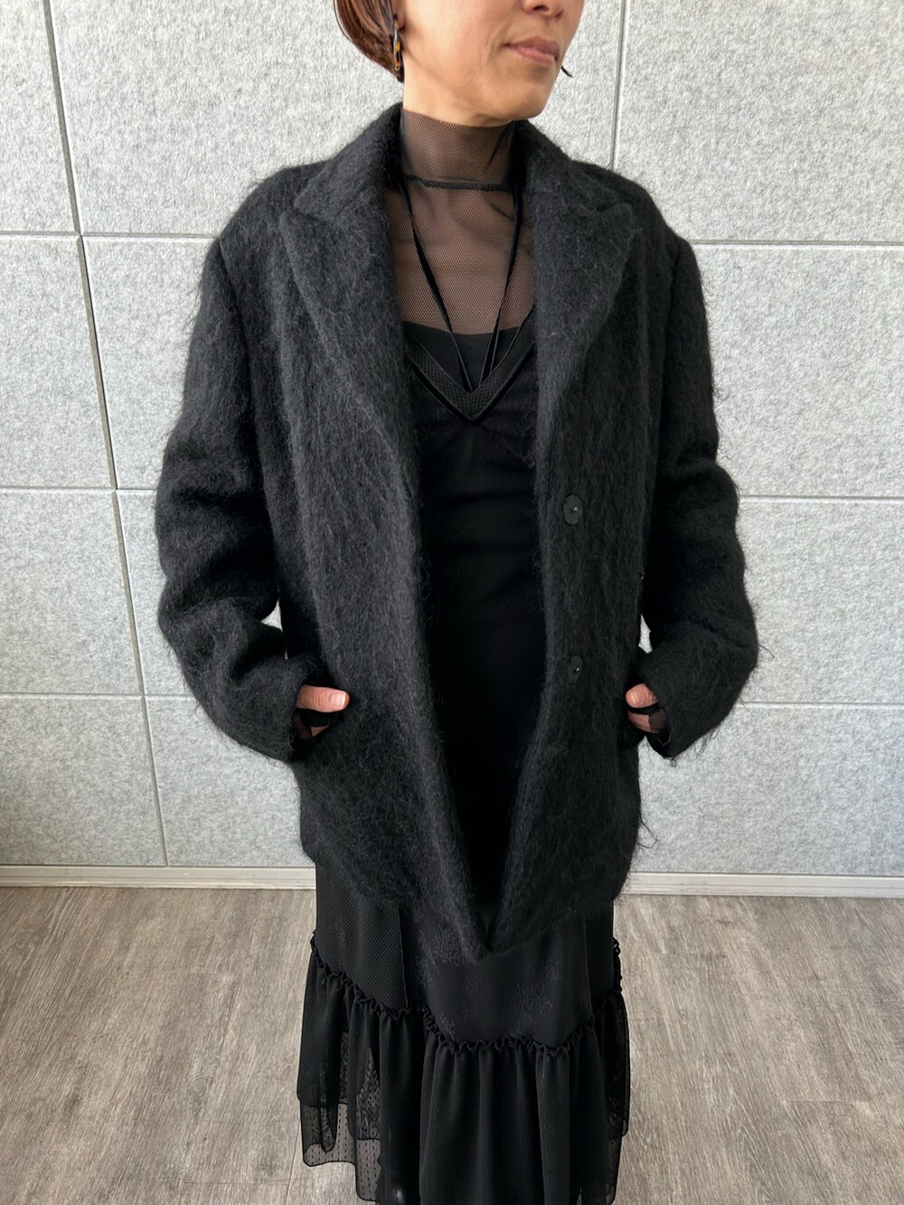 ブラック系のチェスターコート、ブラック系のTシャツ/カットソー、ブラック系のワンピースを着用したレディースの冬コーディネートの4枚目の写真