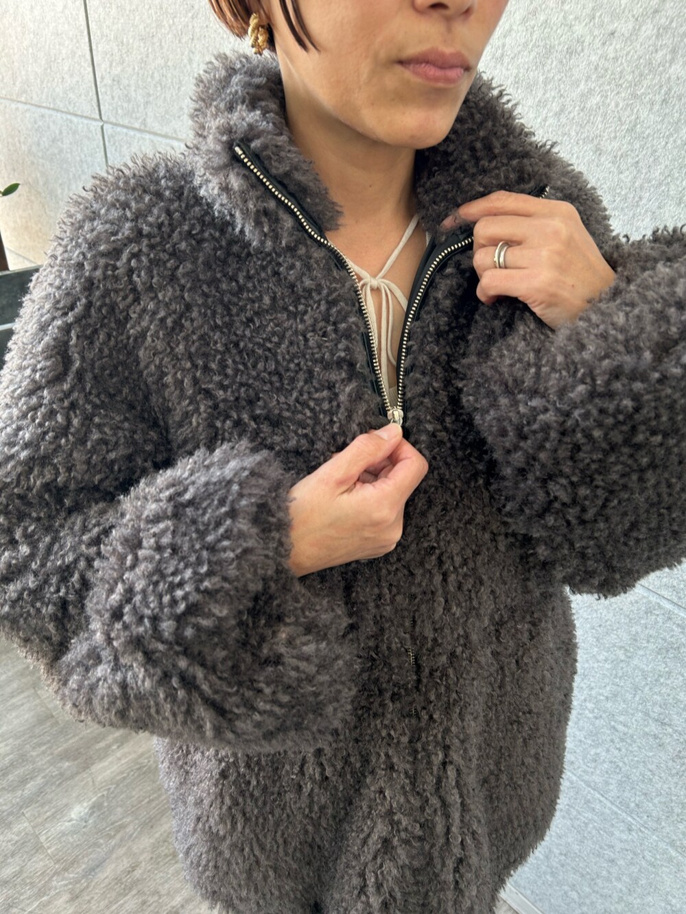 ホワイト系のニット/セーター、グレー系のその他アウター、ブラック系のその他パンツを着用したレディースの冬コーディネートの3枚目の写真