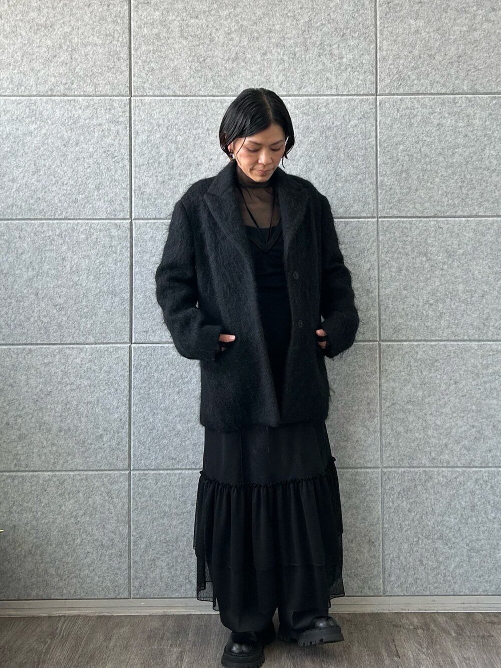 ブラック系のチェスターコート、ブラック系のTシャツ/カットソー、ブラック系のワンピースを着用したレディースの冬コーディネートの2枚目の写真